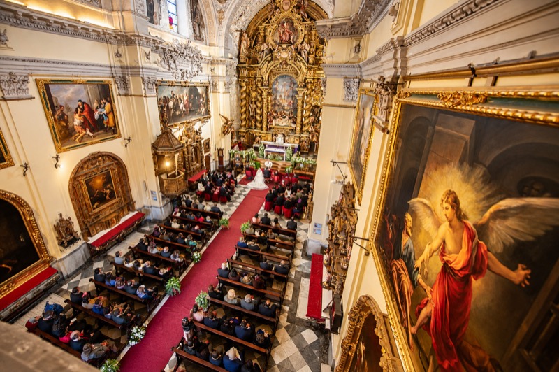 Vista cenital de una ceremonia de boda en una iglesia barroca de Sevilla, con los invitados en los bancos