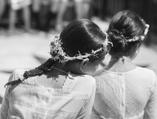 Dos ninas de comunion de espaldas con coronas de flores y trenza, en blanco y negro
