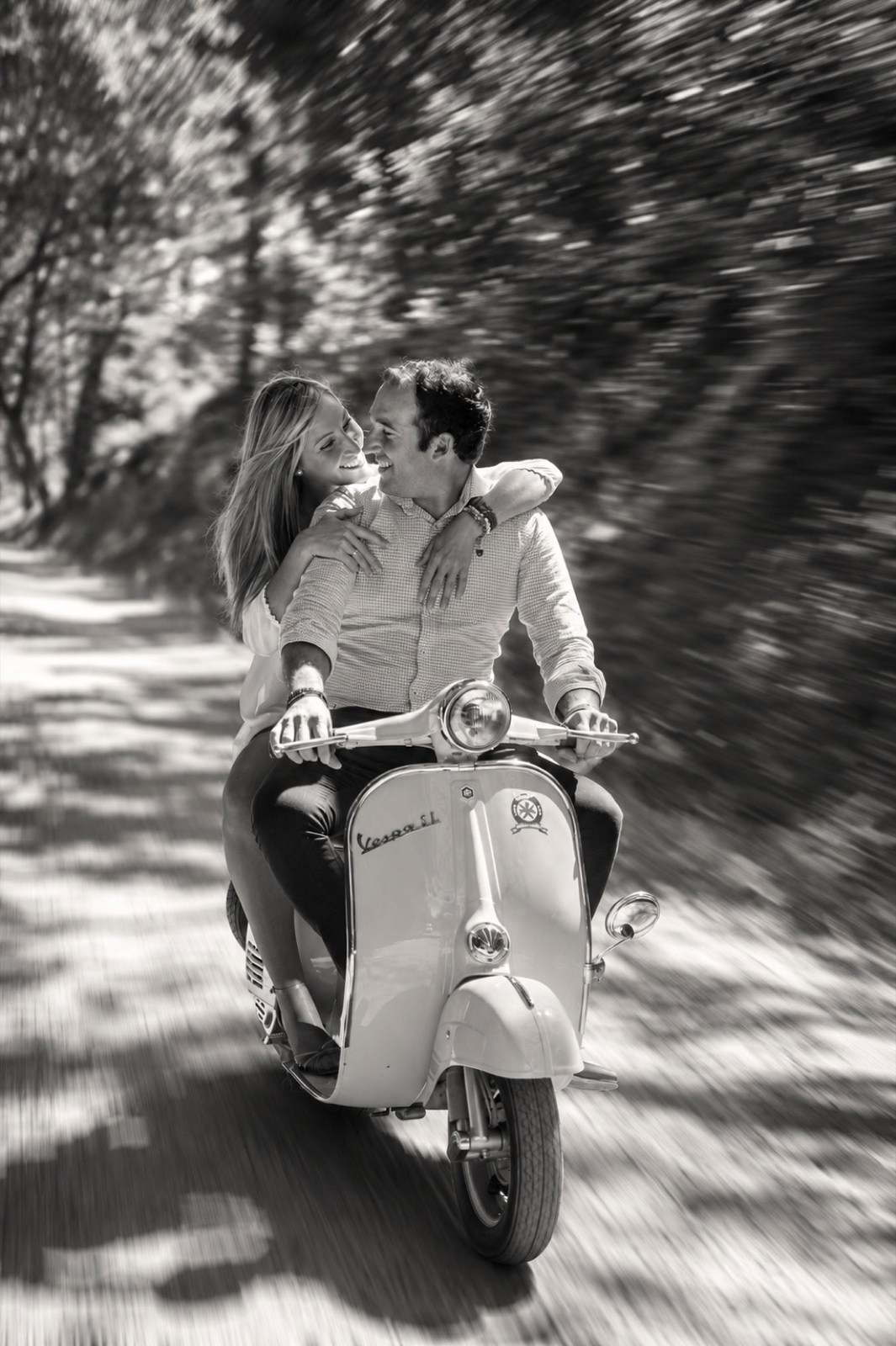 En blanco y negro: la pareja en la Vespa en marcha, mirándose de cerca